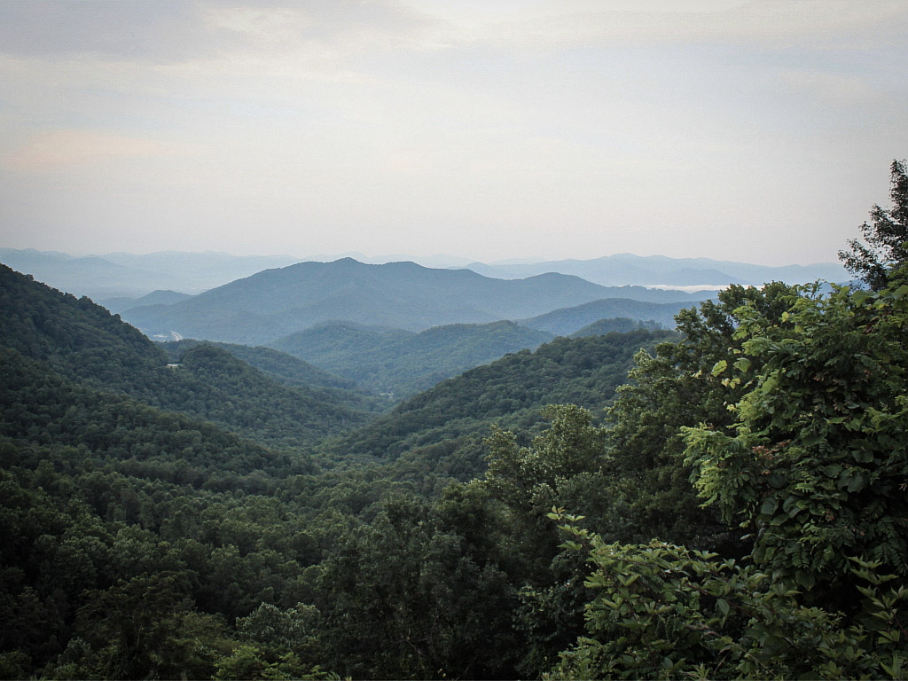 Forested mountain ridges recede into the distance beneath a pale sky in the Nantahala Mountains.