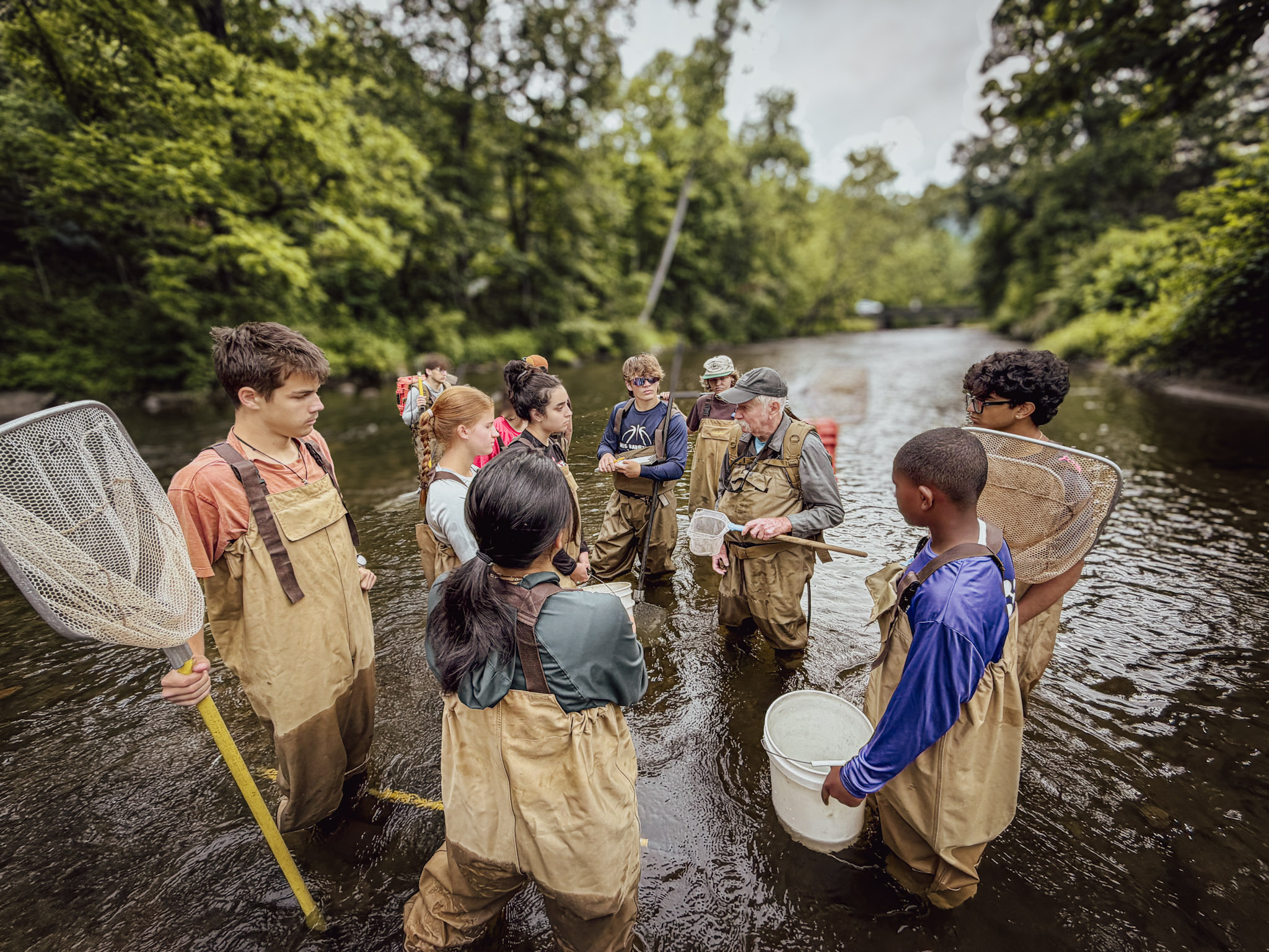 Members of the field team wading in the Cullasaja River with electrofishing equipment.