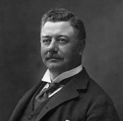 Portrait photograph of Seth Low, with a mustache, in a dark suit